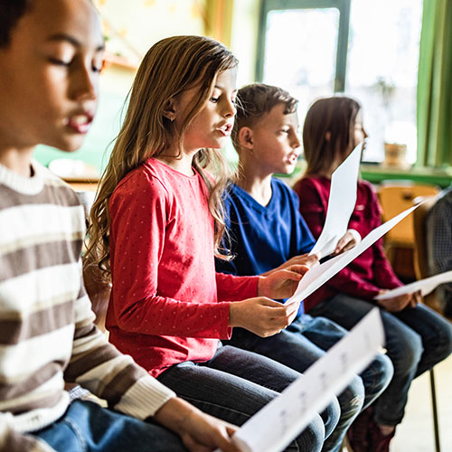 Children with sheet music singing