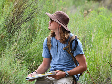 Student sitting alone and Journaling during field work