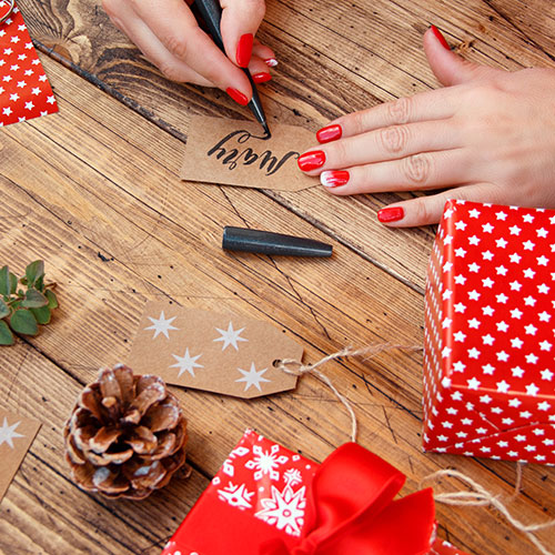 hands writing with calligraphy pen on a gift tag