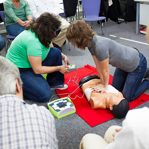 student performing chest compressions on cpr dummy