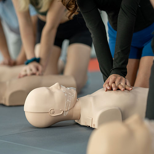 student performing chest compressions on cpr dummy