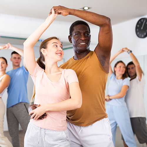 Two dance students learning a dance move in a rumba class
