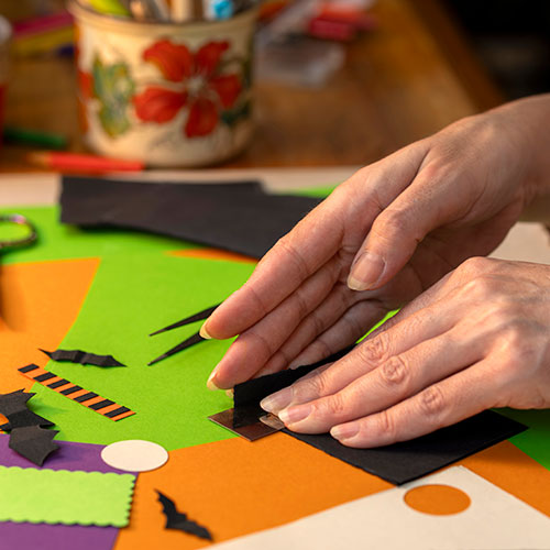 Set of hands folding halloween colored craft paper