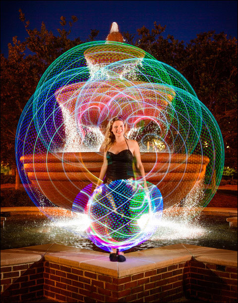 Photograph taken with light of student standing on fountain edge in quad