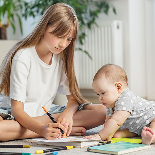 young babysitter playing on floor with infant