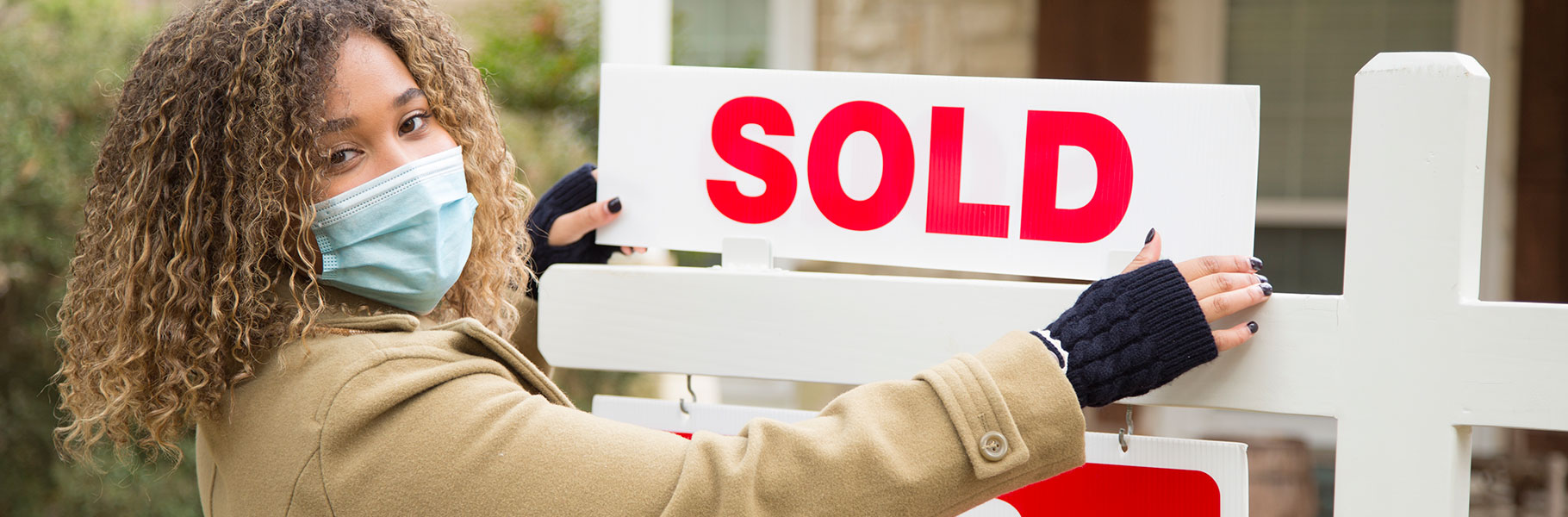 Woman putting sold on real estate sign