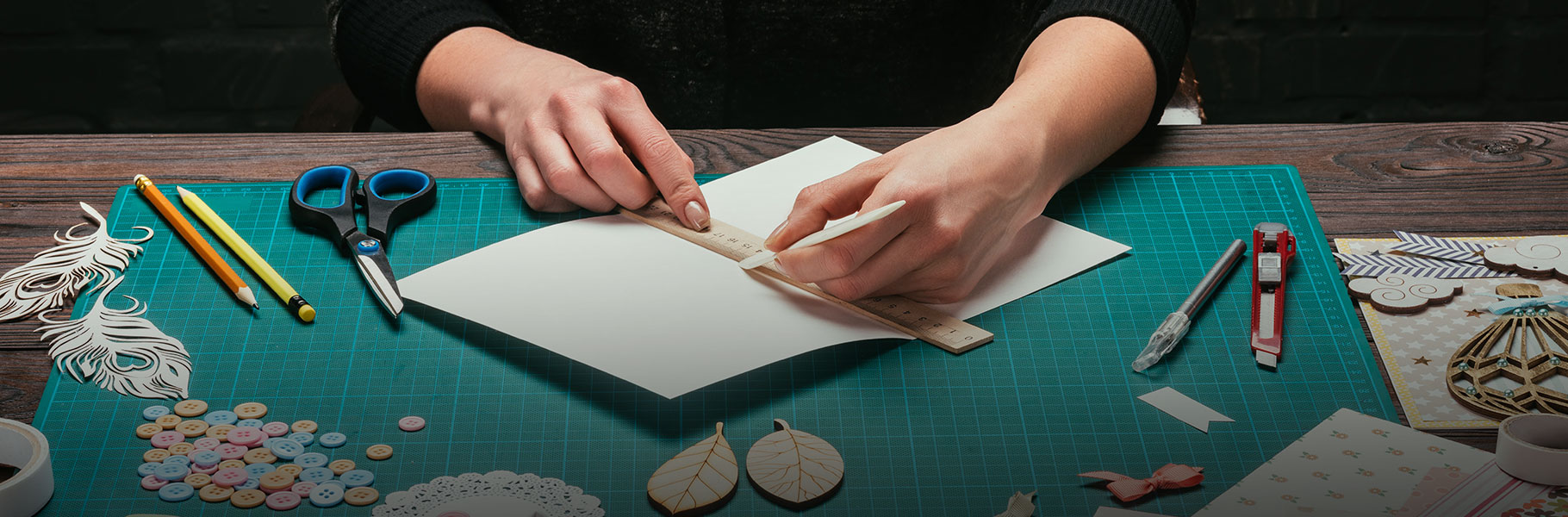 person cutting out card stock on cuttingboard