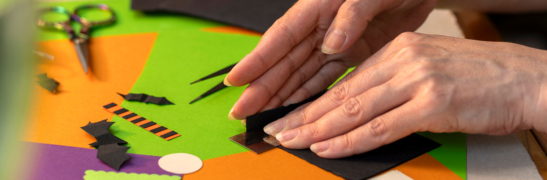 hands working with halloween colored paper making cards