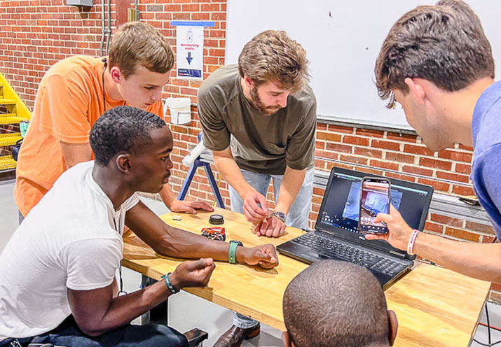 group of students looking at computer screen adn discussing