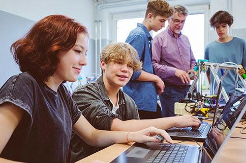 two students in classroom looking at laptop