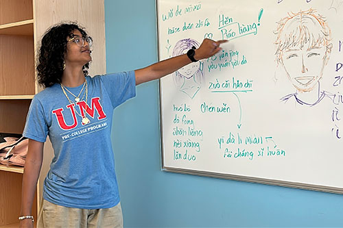 Student pointing at white board with chinese language written on it