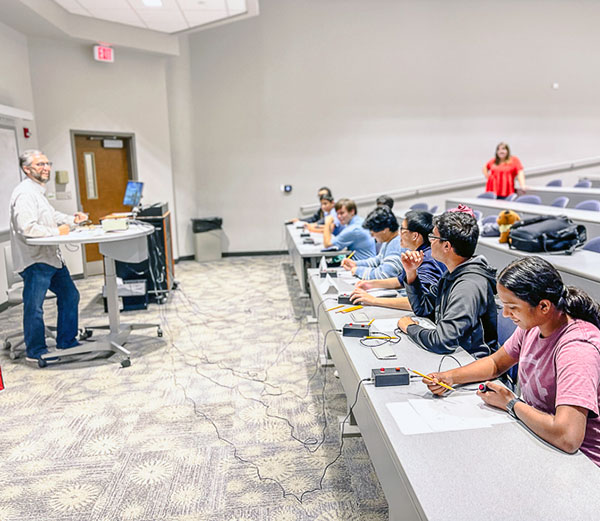 students in classroom with quiz moderator at podium