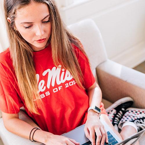 Student wearing Ole Miss shirt working on laptop computer
