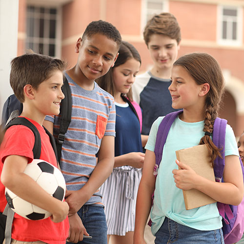 Students in playground while one is holding a soccer ball