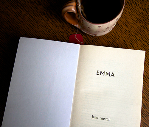 Book and coffee cup opened to page that says emma by jane austen