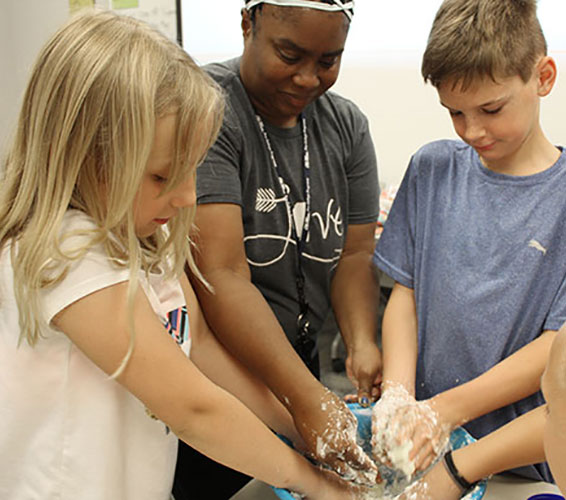 two children and a counselor working with clay