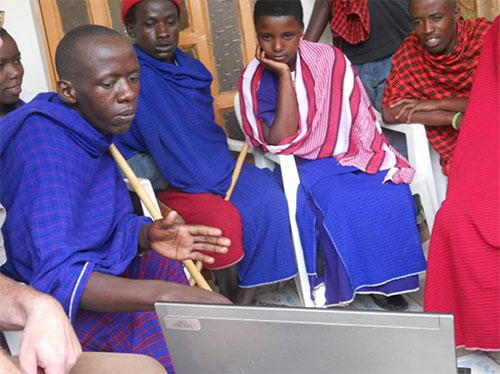 People from Tanzanian community watching a presentation on a laptop computer