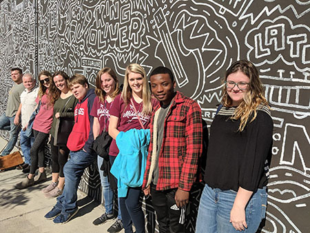 Students posing in front of wall mural