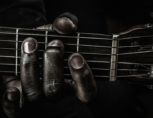 Fingers strumming blues guitar close up