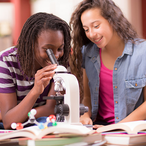 two students looking through microscope